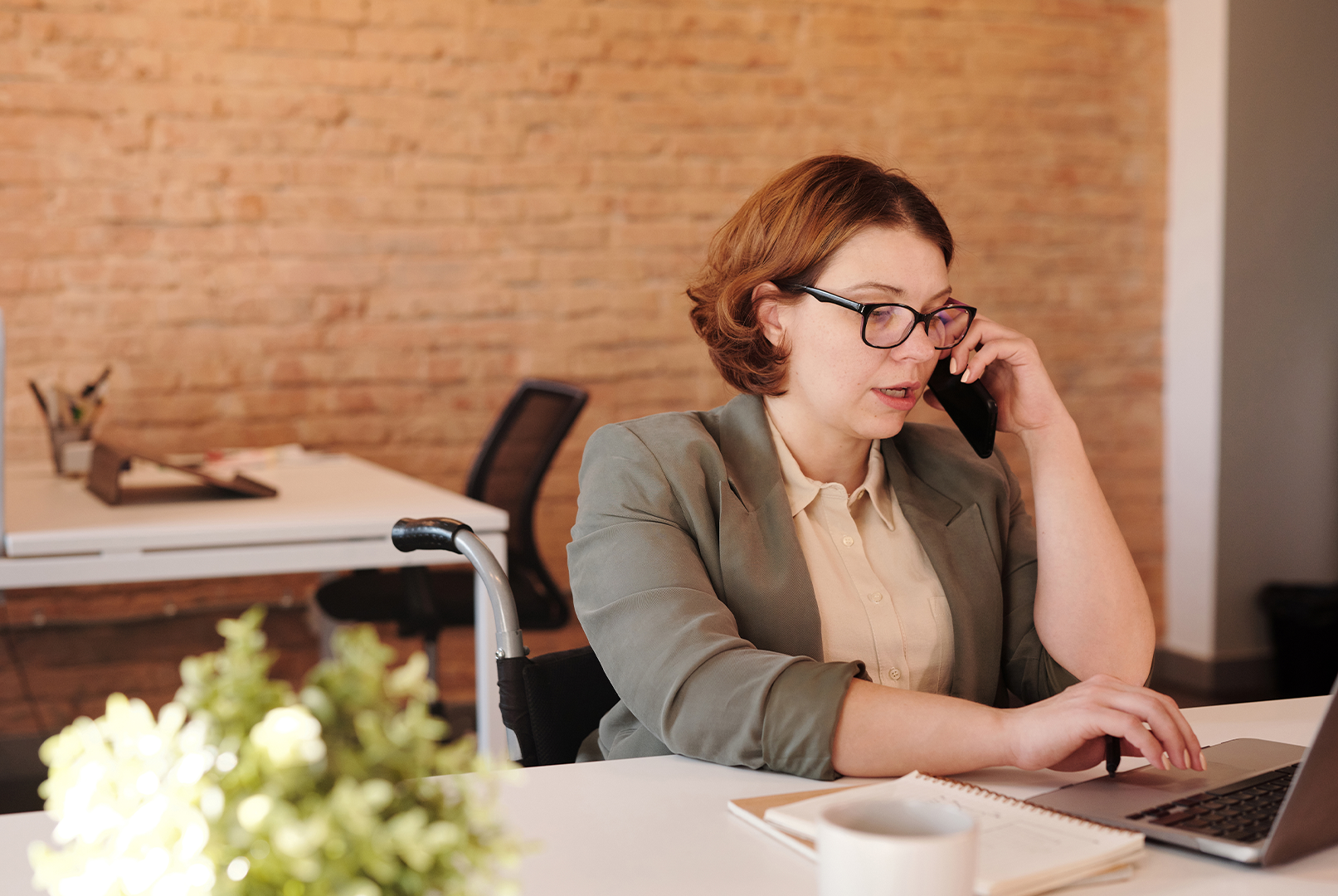 woman sitting at desk on phone