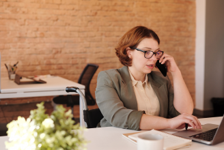 woman sitting at desk on phone