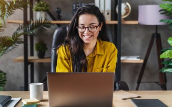 woman with long hair works on laptop at home